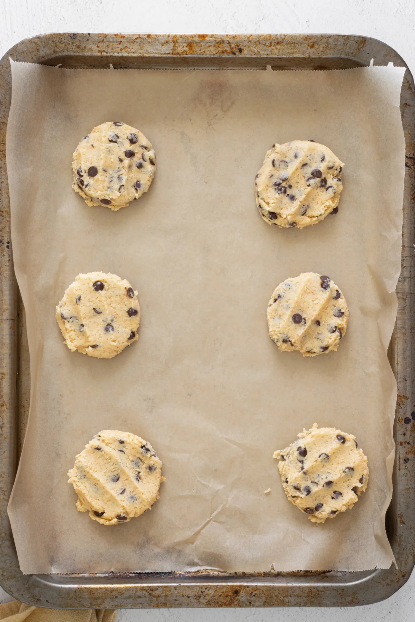 Portioned brown butter cookie dough on a parchment-lined baking sheet